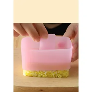 Close-up of pink sushi rice mold being pressed on a wooden cutting board