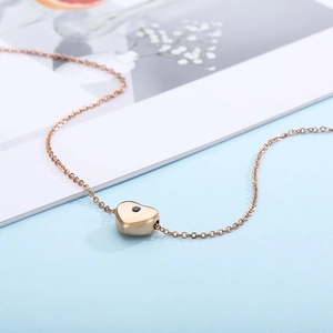 Macro view of rose gold heart pendant with black gemstone inlay on a link chain