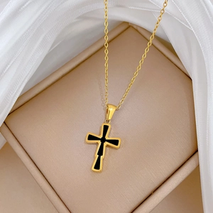 Detail of a gold titanium steel cross necklace with black inlay in a jewelry box