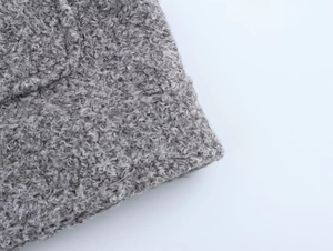 Gros plan détaillé montrant la texture douce de la laine bouclée grise et la finition du tissu