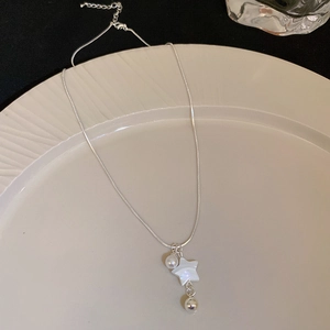 Detail of silver snake chain necklace with pearl and mother of pearl star on ceramic plate