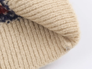 Detailansicht eines beigen Jacquard-Strickpullovers mit Rippbündchen und Musterung