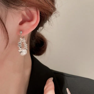 Close-up of geometric silver metal earrings with white pearl drop on a model