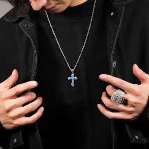 Detail of hip hop cross pendant with blue zircon and iced out ring on male model