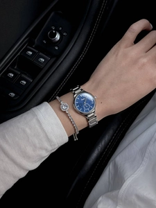 Close-up of women's silver watch with blue dial and matching crystal bracelet on wrist