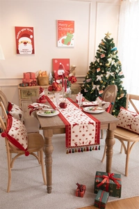Close-up of festive Christmas table runner with reindeer patterns and fringe tassels