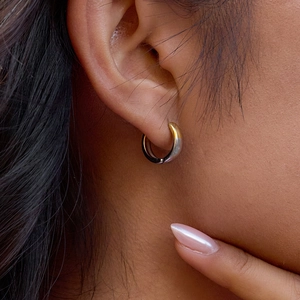 Gros plan de mini créoles bicolores argent et or sur l'oreille de la femme