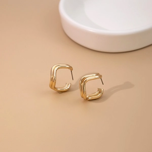 Detail of minimalist gold square earrings with a layered double-line geometric design