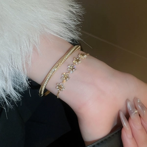 Close-up of gold-plated star and flower bracelets with cubic zirconia on a wrist
