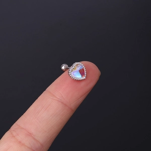 Macro view of a colorful heart-shaped lab-opal ear stud with steel screw back on finger