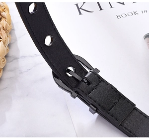 Detailed close-up of punk style black leather belt with metal buckle and eyelets