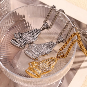 Macro shot of gold and silver praying hands pendants with diamonds on twist chains