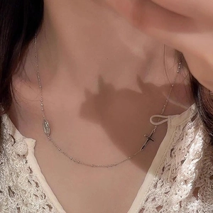Collier argenté avec croix et pendentif ovale porté par un modèle pour style plage
