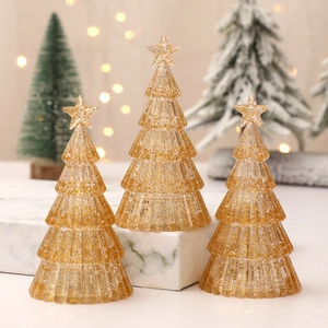 Three transparent mini Christmas trees with gold glitter and star tops on marble base