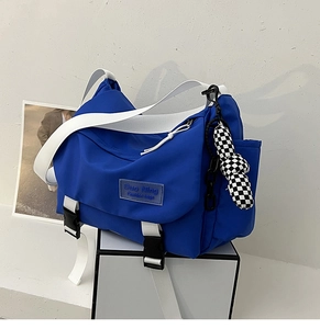 Detail of blue nylon crossbody bag featuring white adjustable strap and checkerboard charm