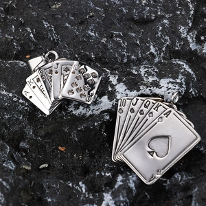 Detailed view of two Ace of Spades poker card pendants on a dark volcanic rock background
