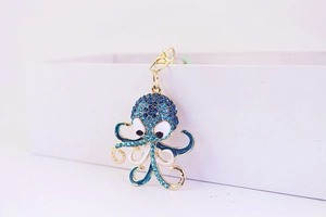 Close-up of cute octopus keychain with blue crystals and enamel on gold plating