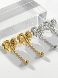 Close-up of bow tassel earrings in gold and silver finish with elegant metal chains