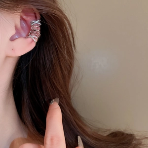 Detail view of silver multi-layer crisscross ear cuff with zircons worn on ear