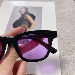 Close-up of black square sunglasses with purple lenses and silver dot detail