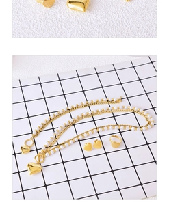 Detail of gold heart pendant pearl necklace set with matching heart studs and ring