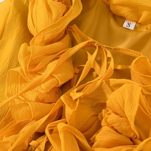 Macro detail of yellow chiffon top featuring ruffled edges, drawstring, and size S label