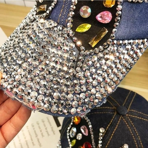 Close-up of colorful rhinestones and crystal butterfly design on distressed denim baseball cap