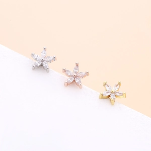 Macro detail of heart and star shaped flower earrings in silver, gold, and rose gold finishes