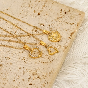 Three elegant gold heart necklaces with zircon inlay and vintage patterns on stone surface