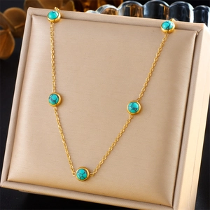 Vintage gold chain necklace featuring five turquoise stone beads on a beige jewelry case