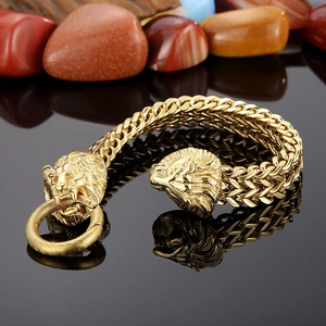 Macro detail of men's golden lion head bracelet with thick woven stainless steel chain