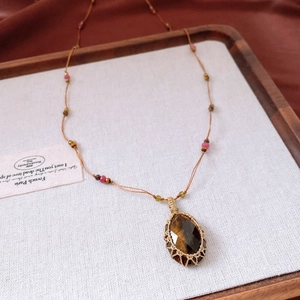 Detail of hand-woven tiger eye stone pendant with gold wire mesh on a vintage beaded cord