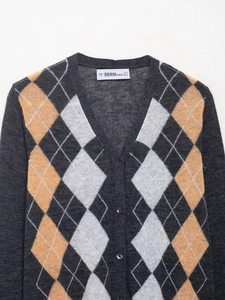 Close-up of V-neck argyle knit cardigan with orange and cream diamond patterns