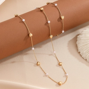 Golden heart and pearl necklace set on velvet background with seashell decoration