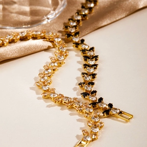 Detailed shot of gold leafy bracelets with black and white marquise-cut sparkling zircons