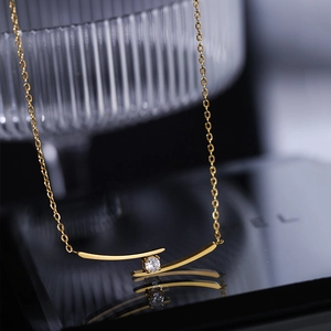 Elegant gold-plated curve bar necklace with a centered zircon on a black mirror surface