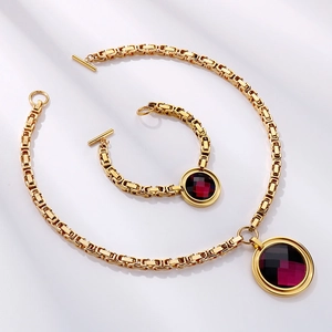Detail of gold toggle clasp necklace and bracelet with red faceted glass stone charms
