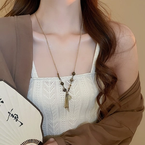 Dettaglio di una collana lunga vintage con nappe, perline e ciondoli a moneta oro