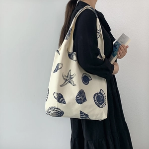 Close-up of white canvas tote bag featuring navy blue sea shell and starfish prints