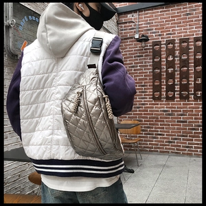 Silver quilted waist bag with adjustable strap shown on model in an outdoor cafe setting