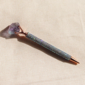 Macro detail of rose gold pen with purple crystal top and sparkling silver rhinestones