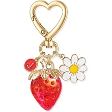 Detail view of gold keychain with red strawberry, white daisy, and red letter J charm