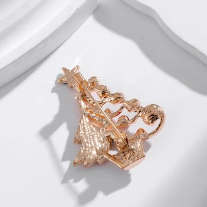 Back view of gold Christmas tree brooch with safety pin fastener on a white stone background
