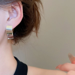 Macro shot of silver square geometric stud earrings with polished mirror finish