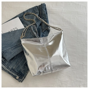 Detail of silver metallic tote bag featuring vertical stitching and woven chain strap