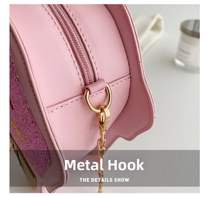 Close-up of golden metal hooks and pink glitter accents on a cute fashion crossbody bag