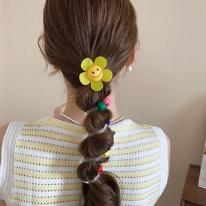 Détail de la pince à cheveux fleur jaune et des élastiques spirales colorés sur queue de cheval