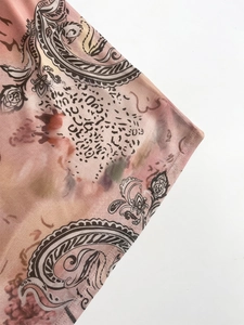 Detail of mesh fabric featuring paisley and leopard prints with pink and orange tie-dye style