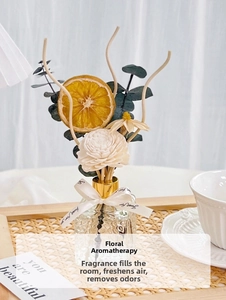 Detail of flower reed diffuser set with preserved orange slices and floral accessories