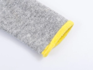 Detail of grey knitted cardigan showing bright yellow contrast trim and thick fiber texture